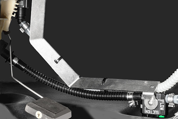 Close-up of a mechanical component with a black hose and metal bracket on a dark background
